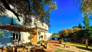 Una casa con un patio, mobiliario exterior y un jardín.