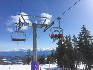 A ski lift with passengers, a mountain view, and a clear sky.