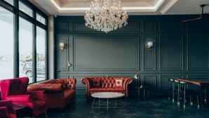 Un salón moderno con un sofá de cuero, sillas rojas, una mesa de centro redonda y una araña.