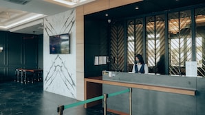 Una zona de recepción con pared de mármol, mostrador de recepción y diseño interior moderno.