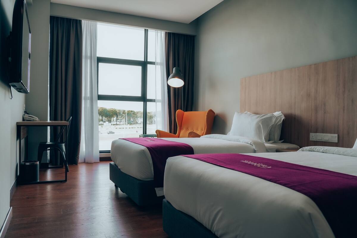 Une chambre d’hôtel avec deux lits, un bureau et une chaise.
