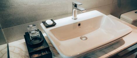 A bathroom with a white sink, a mirror, and a towel dispenser.