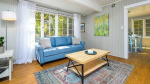 Una sala de estar con un sofá azul, una mesa de centro de madera y una alfombra colorida.