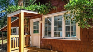 Una cabaña de madera con un porche, una puerta y una ventana.