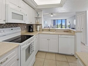 A kitchen with white cabinets, a microwave, stove, and dishwasher.