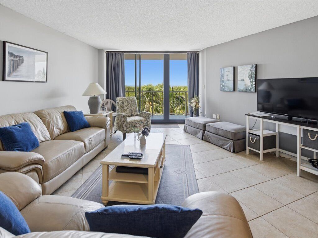 Een moderne woonkamer met een bank, salontafel, televisie en een balkon met uitzicht.