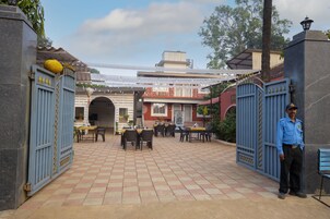 Un patio con piso de baldosas, mobiliario exterior y un guardia de seguridad.