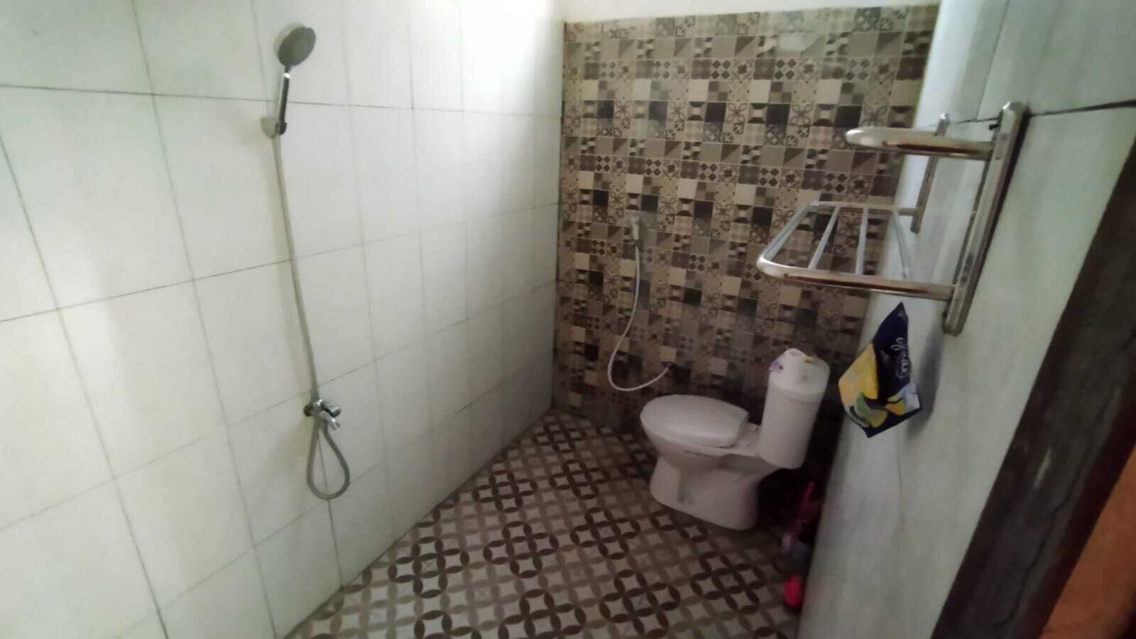 A small bathroom with a shower, toilet, and tiled floor.