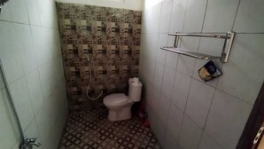 A small bathroom with a toilet, a shower, and a tiled floor. - Borobudur Kampung Homestay - Suparlan (Magelang)