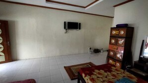 A room with a bed, a television mounted on the wall, a cabinet with drawers, and a tiled floor. - Borobudur Kampung Homestay - Suparlan (Magelang)