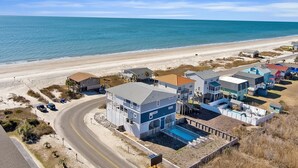 A coastal residential area with houses, a swimming pool, and a beach. - Rushin to the Beach: Spacious 8-bedroom oceanview home in Oak Island, perfect for families. (Oak Island)
