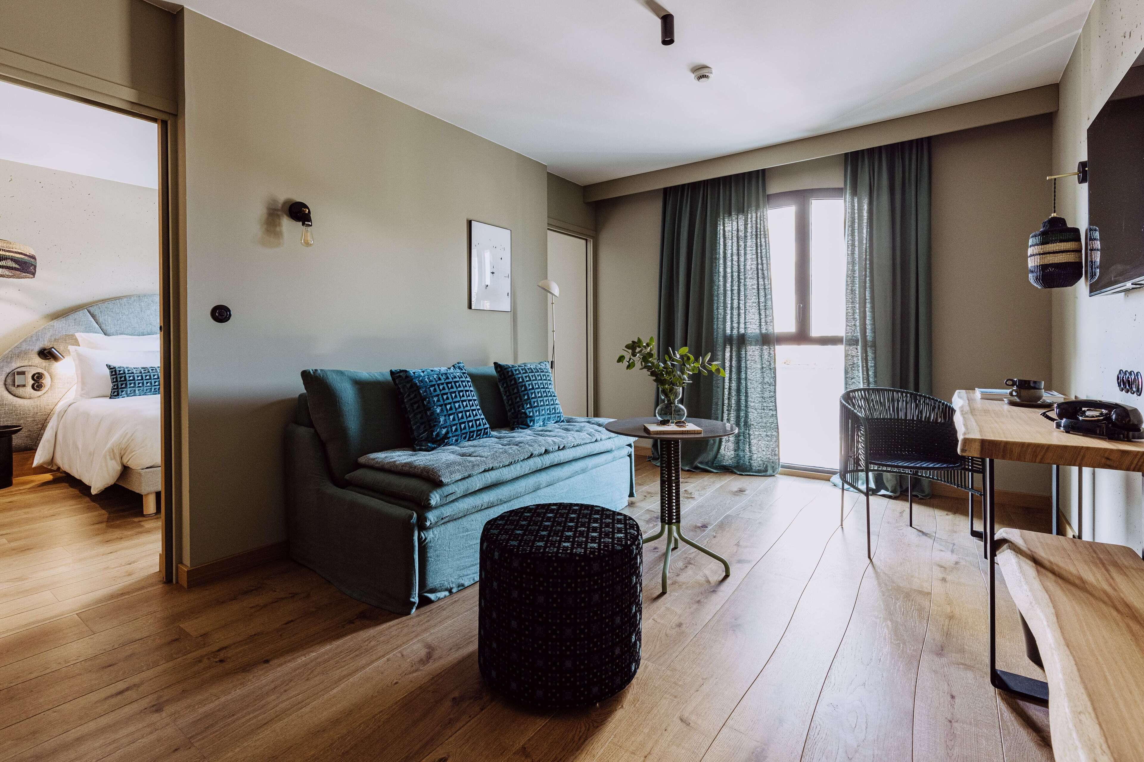 Uma sala de estar moderna com sofá, banquinho e um espaço de jantar com mesa e cadeiras.