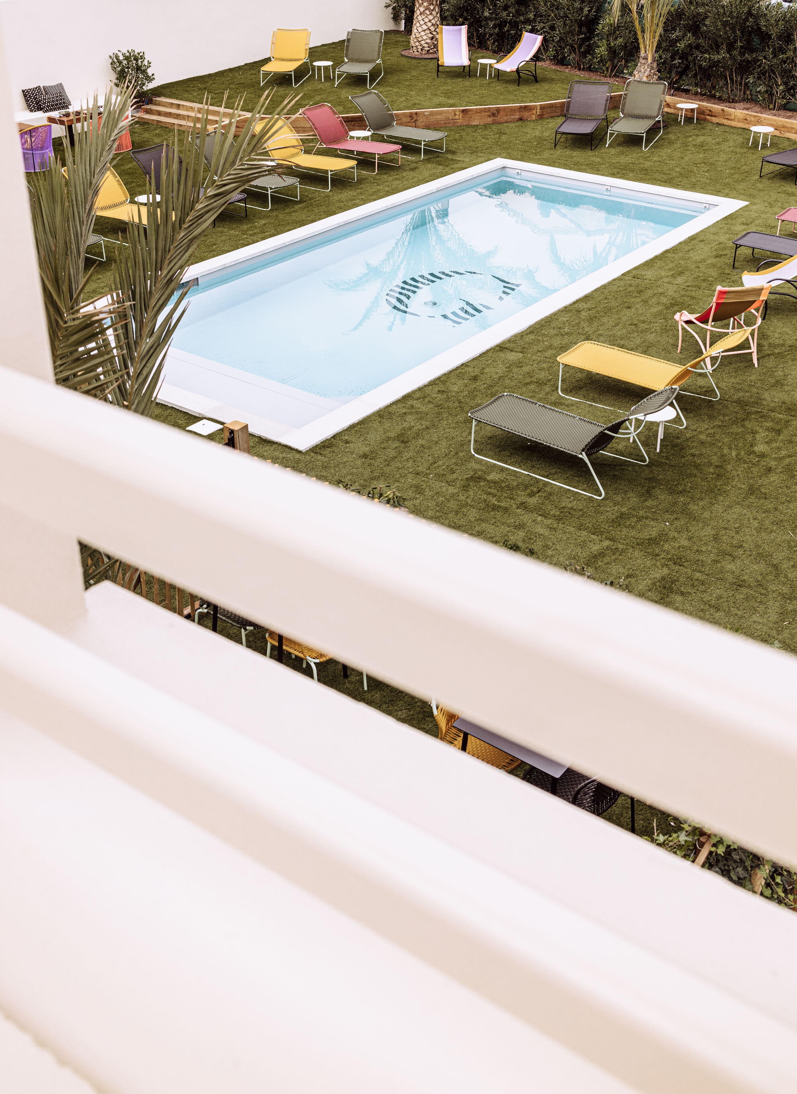 Ein Poolbereich mit mehreren Liegestühlen und einem kleinen Tisch, umgeben von Kunstrasen und einer Holzterrasse.