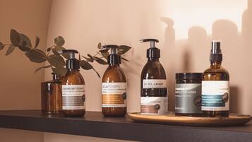 A shelf with four bottles of body care products and two woven baskets on a table.