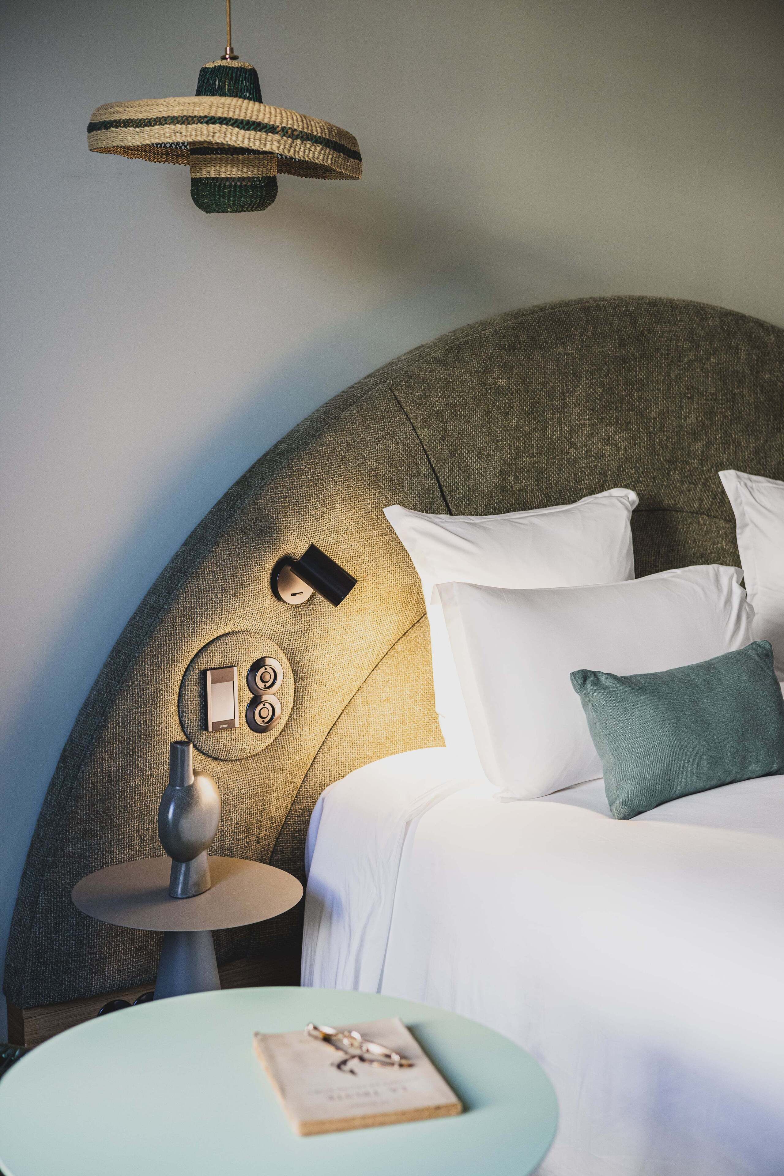 A neatly arranged bedroom with a large bed, a bedside table, a lamp, and a hanging light fixture.