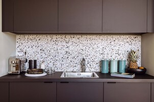 Una cocina con salpicadero moteado, un lavamanos de acero inoxidable y una cafetera.