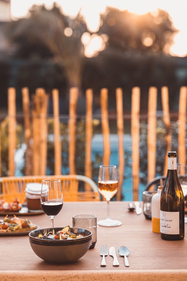 Una mesa de comedor con un bol de comida, copas de vino, una botella de vino y cubiertos.