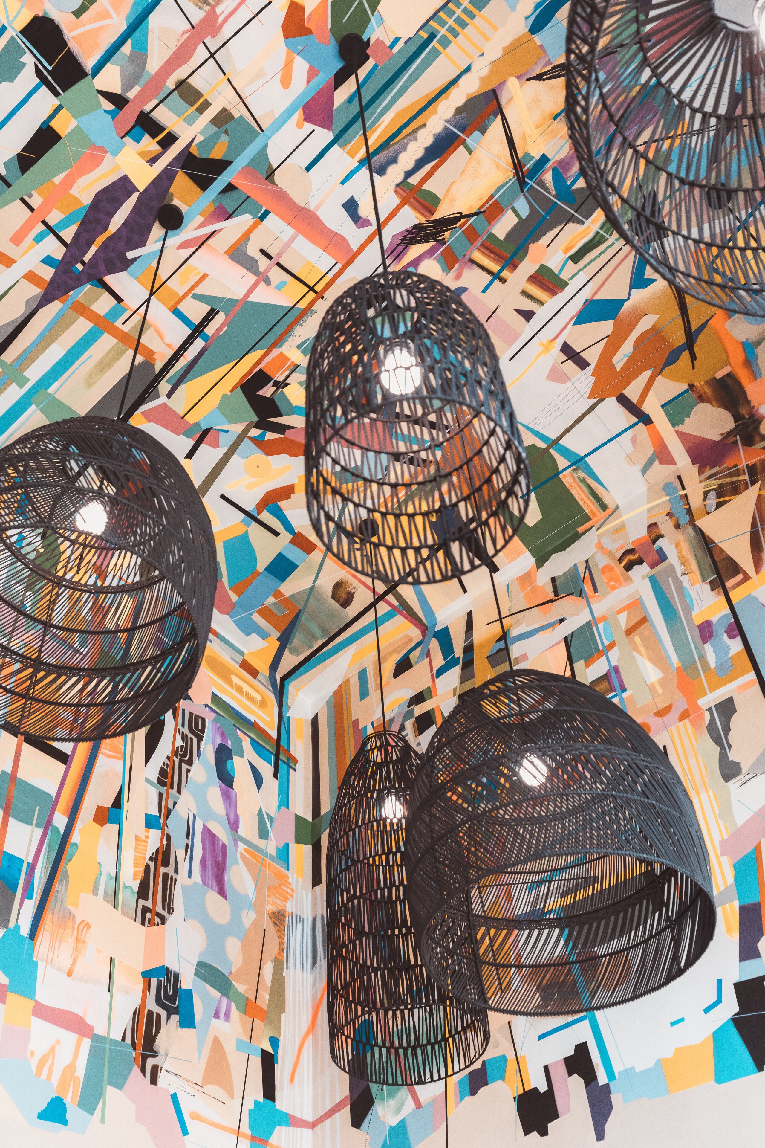 Un plafond orné de motifs géométriques et de lampes noires suspendues.