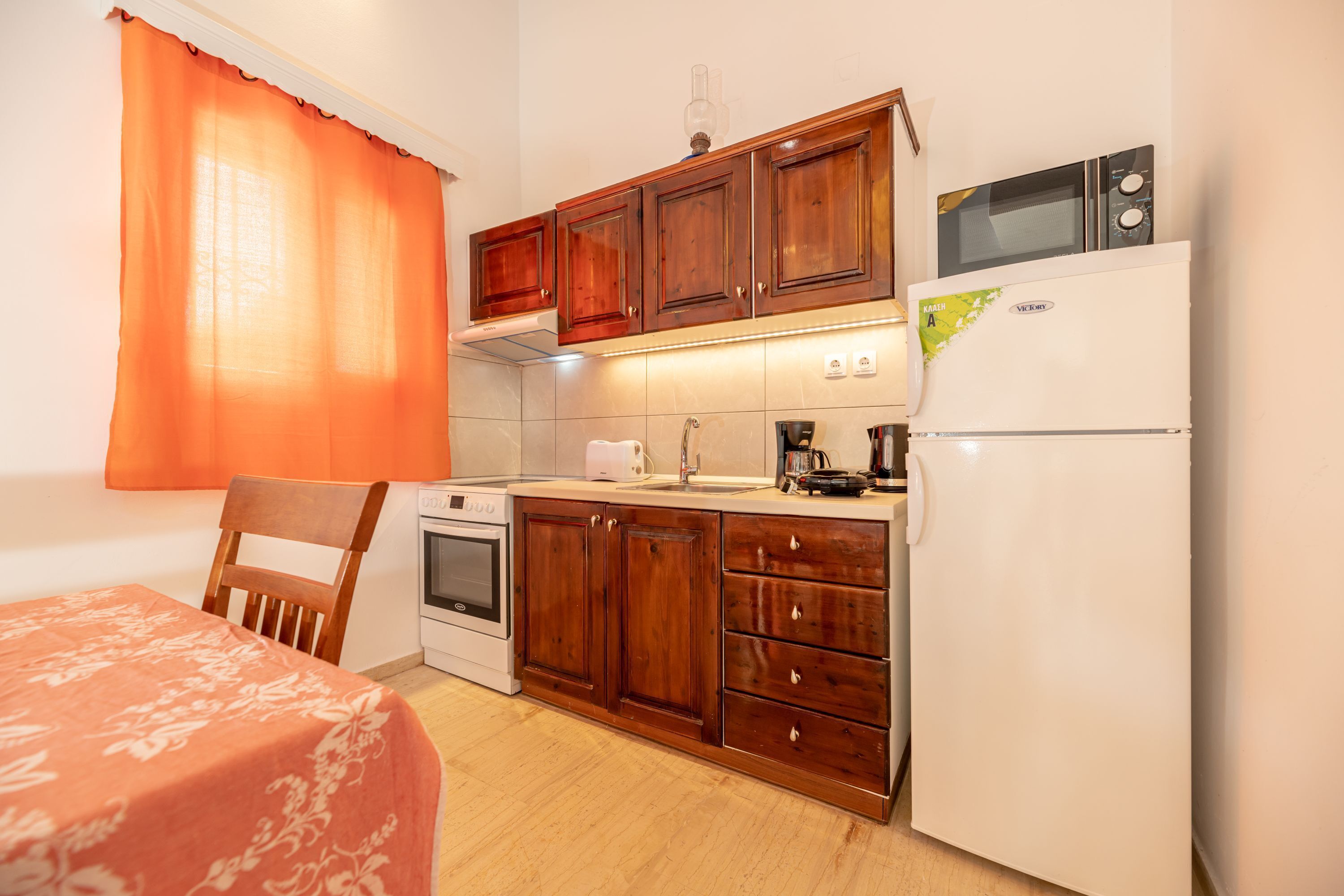 A compact kitchen with wooden cabinets, a white refrigerator, a microwave, and a stove.