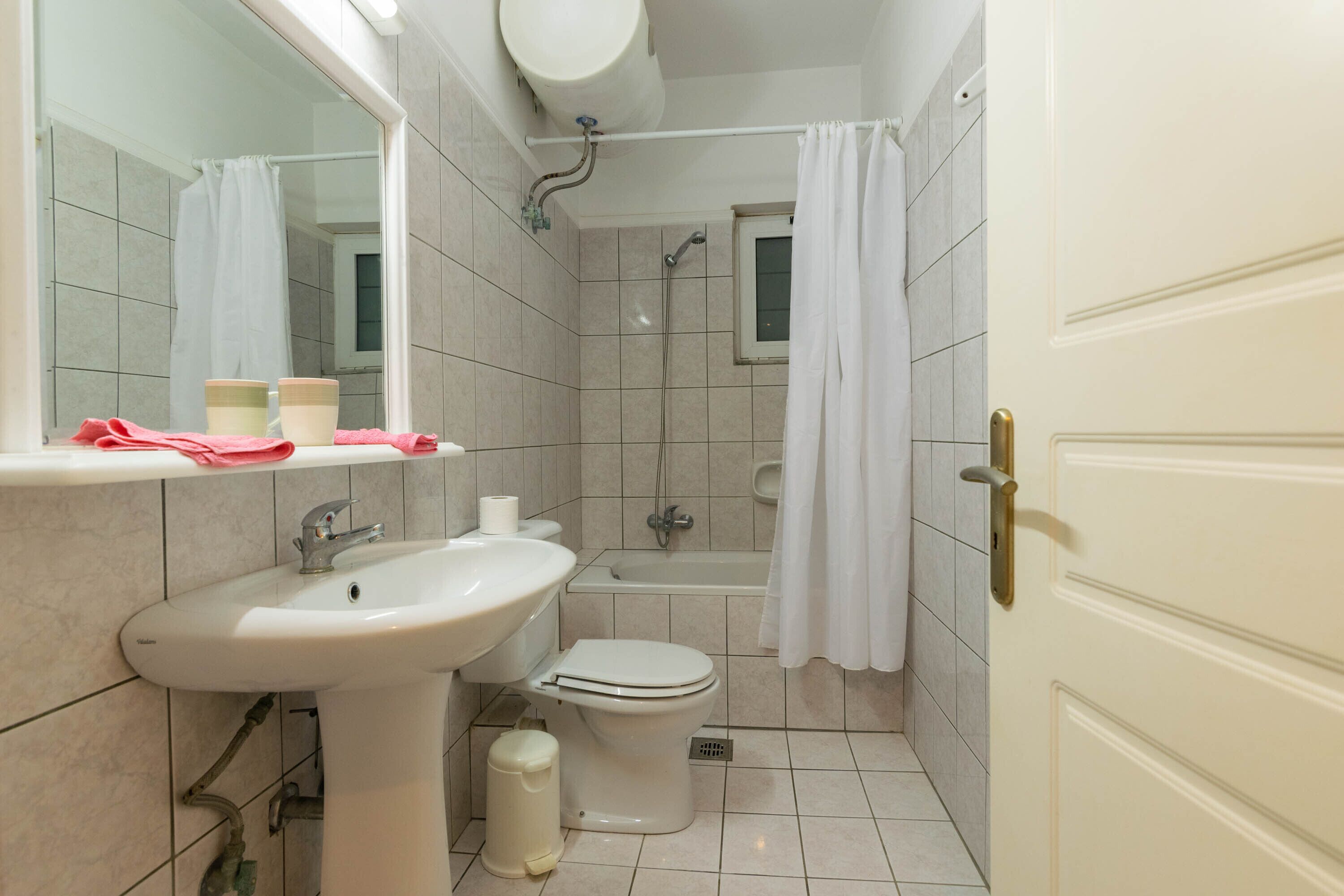 Et badeværelse med vask, toilet og badekar.