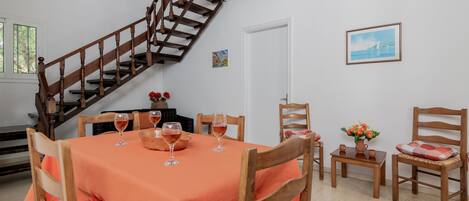 A dining area with a wooden staircase, a table set with wine glasses, and chairs with cushions.