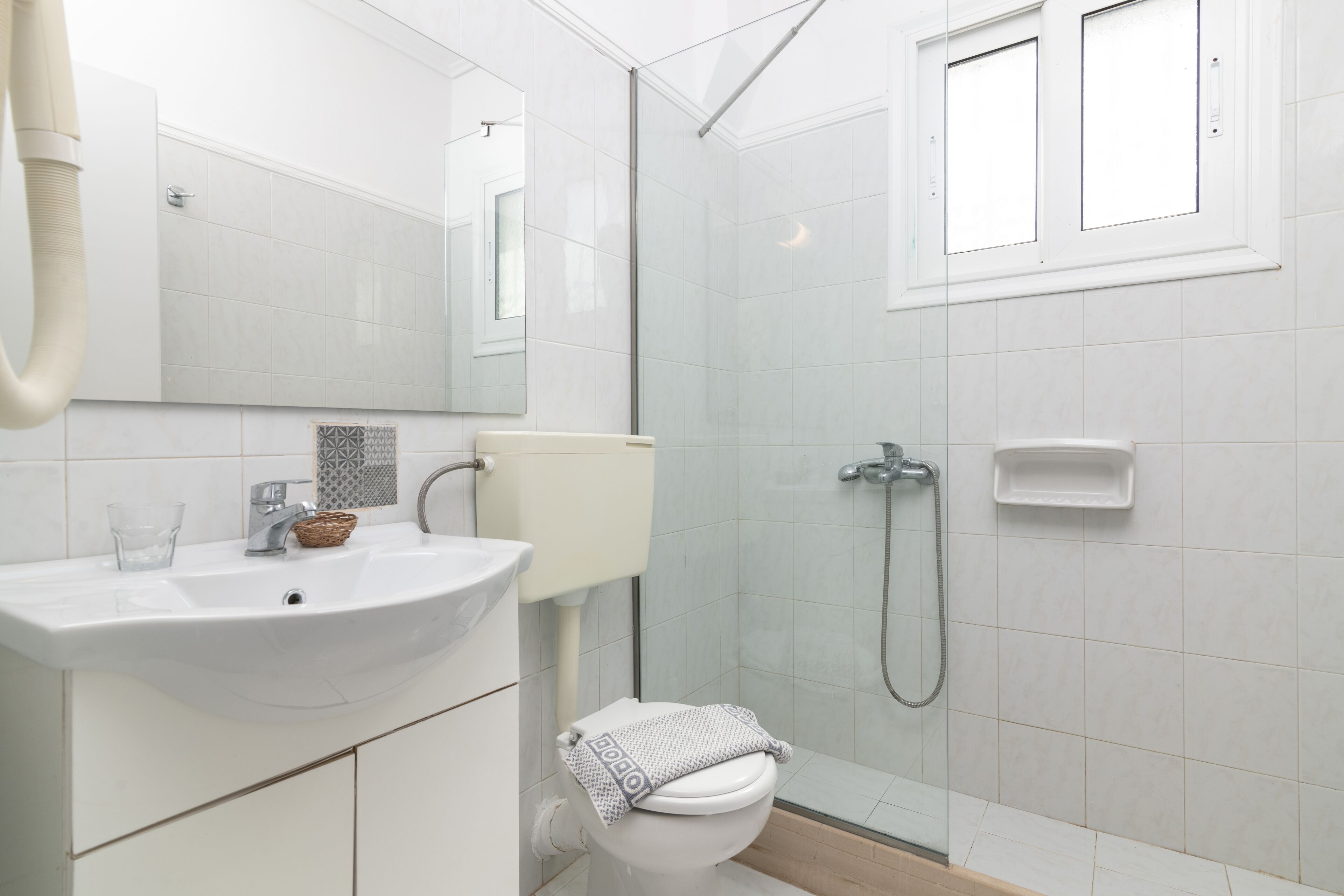 A modern bathroom with a white sink, toilet, and shower.