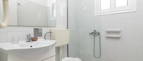 A modern bathroom with a white sink, toilet, and shower.