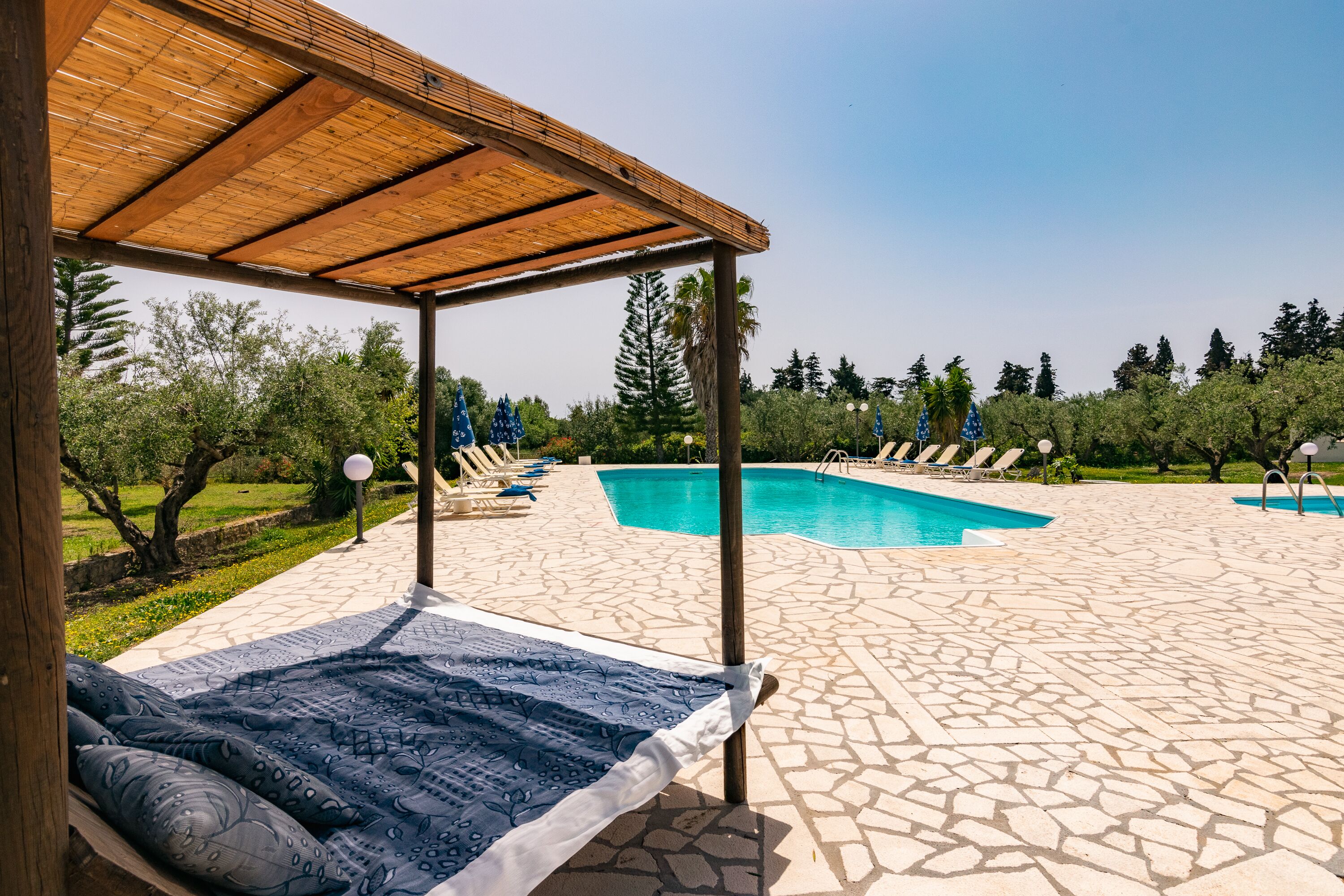 Ett poolområde med en pergola, solstolar och en klarblå pool.