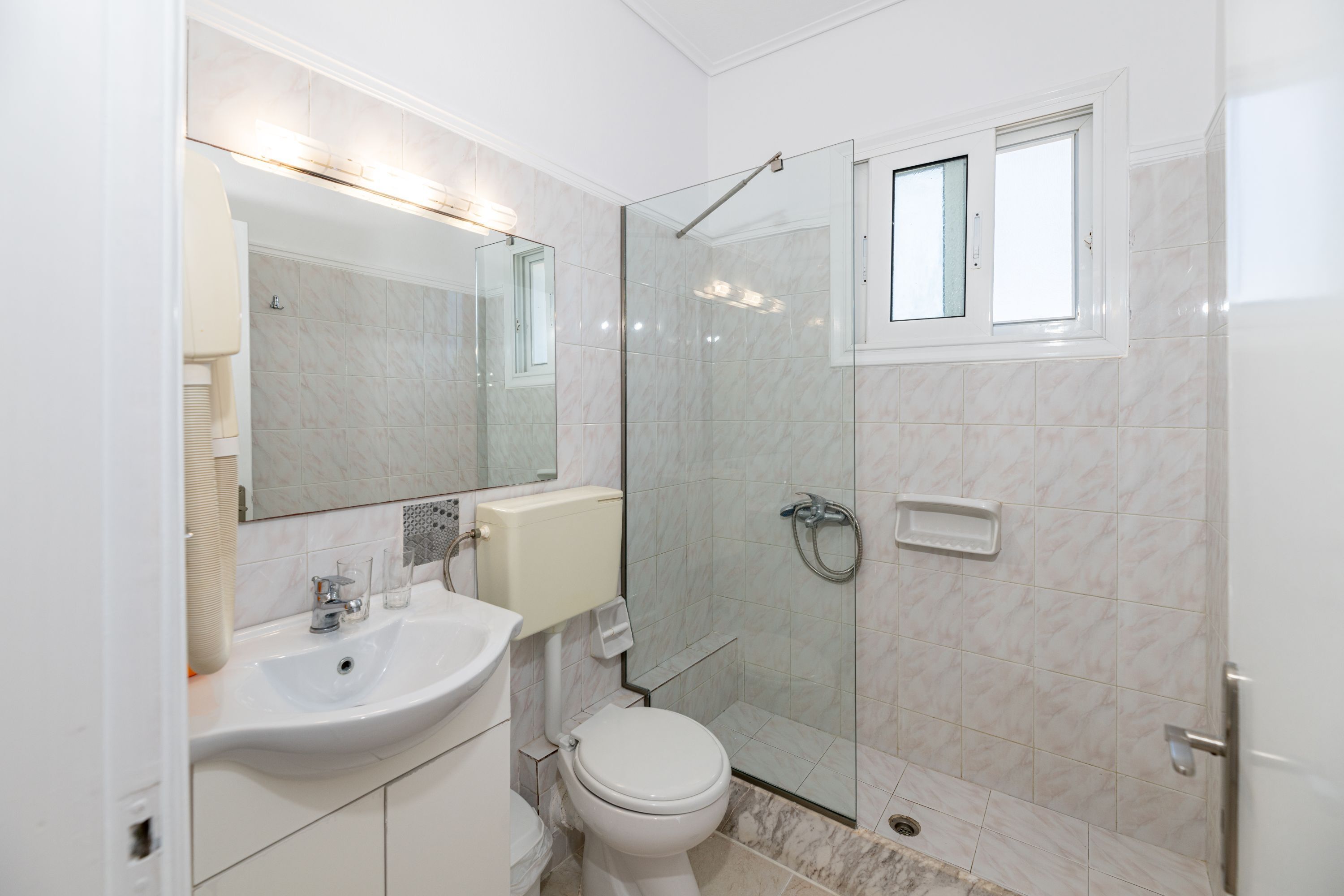 A modern bathroom with a glass-enclosed shower, a sink, and a toilet.