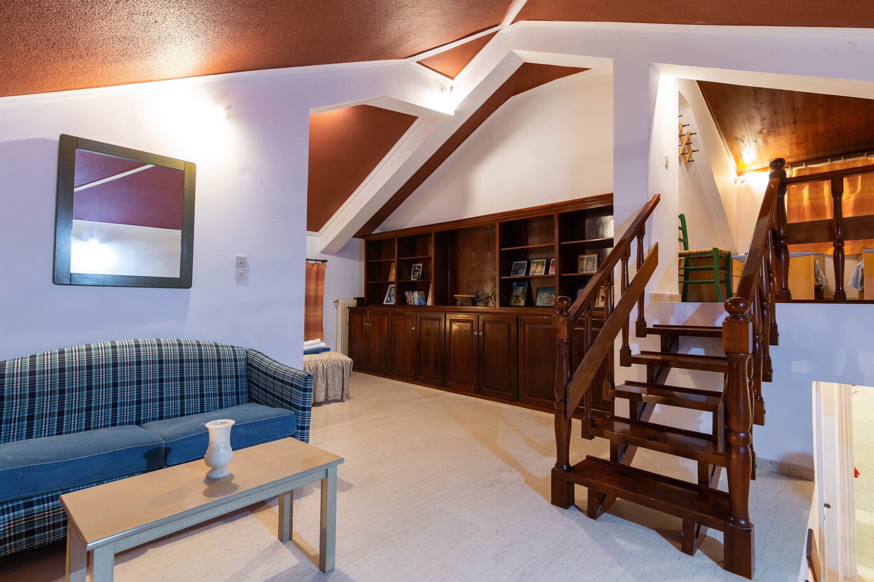 A living room with a blue sofa, wooden staircase, and a built-in bookshelf.