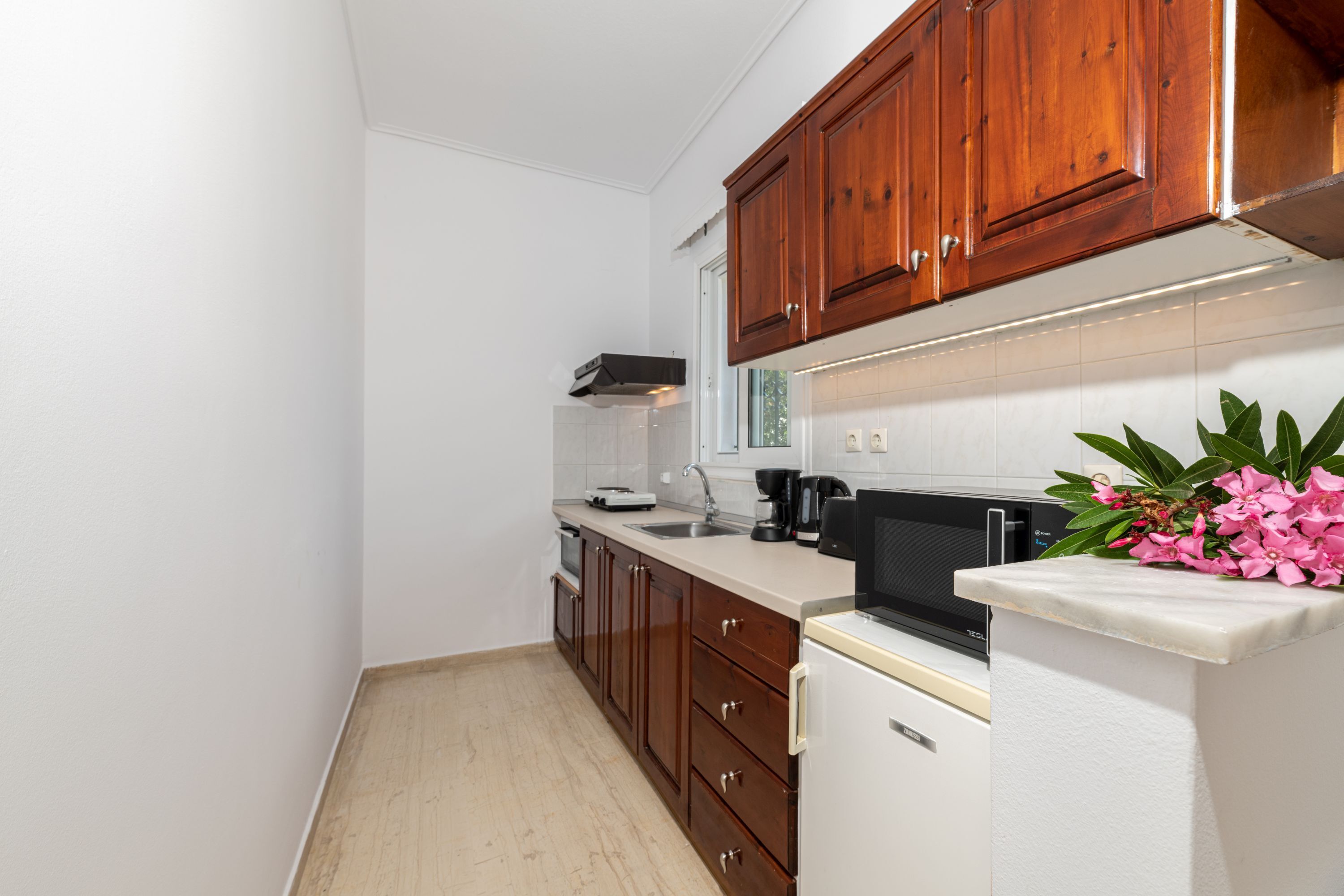 Eine Küche mit Holzausstattung, einem weißen Kühlschrank, einer Mikrowelle und einem Spülbecken.