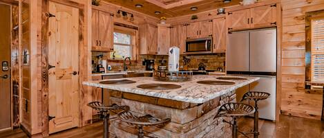 A wooden cabin-style kitchen with a central island, bar stools, and built-in appliances.