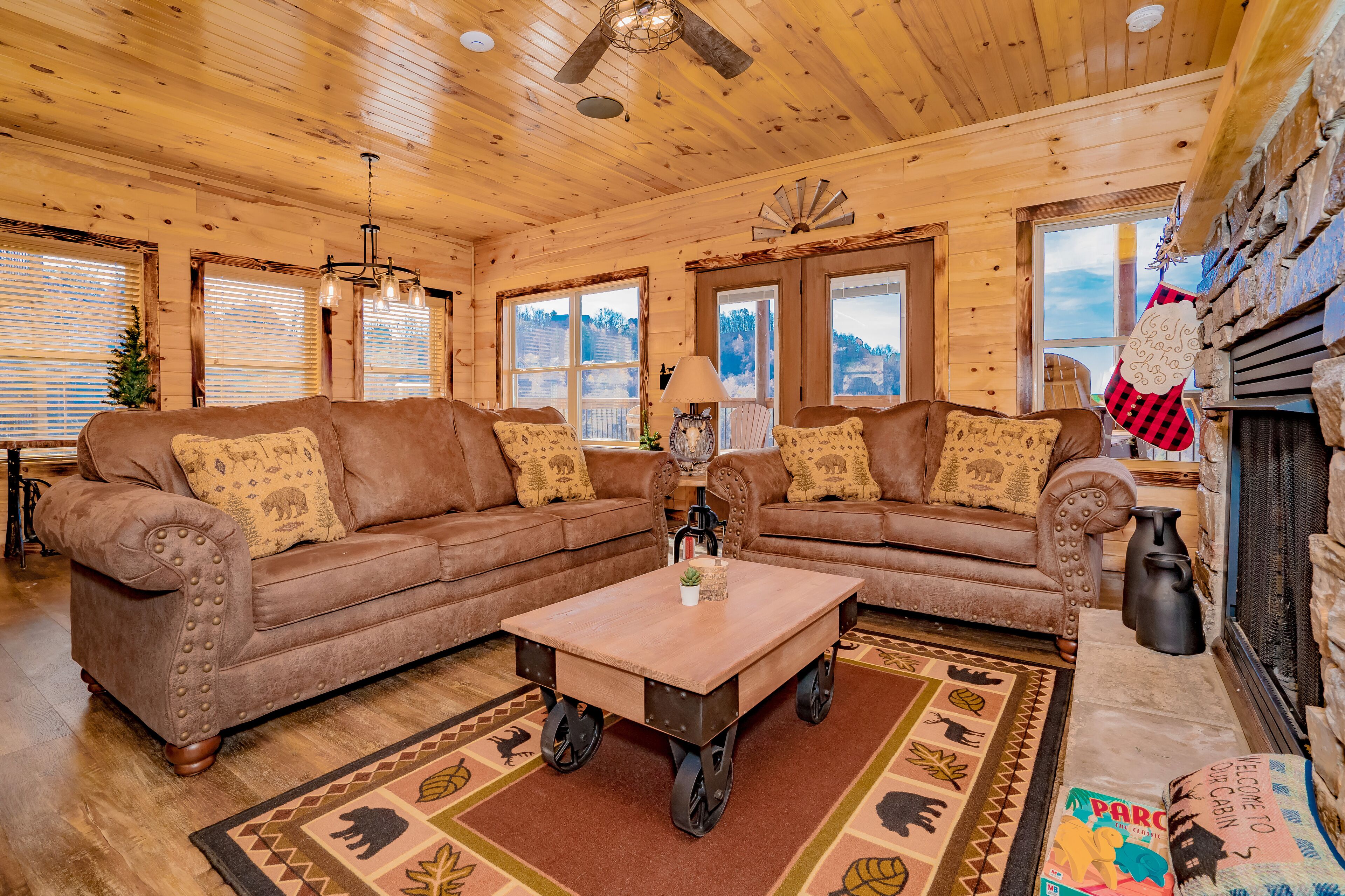 Ein gemütliches Blockhaus-Interieur mit zwei braunen Ledersofas, einem Holztisch und einem gemusterten Teppich.