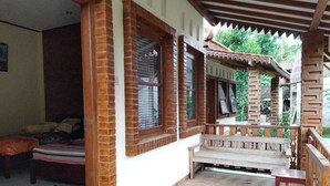 A room with a bed, a wooden bench, and a window with a view of greenery outside.