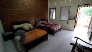 Una habitación con dos camas, un ventilador y una silla.