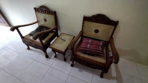 Two ornate wooden chairs with woven backs and seats, a small square table, and a plain wall.