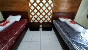 A room with two beds, each with a mattress and pillows, and a wooden headboard.