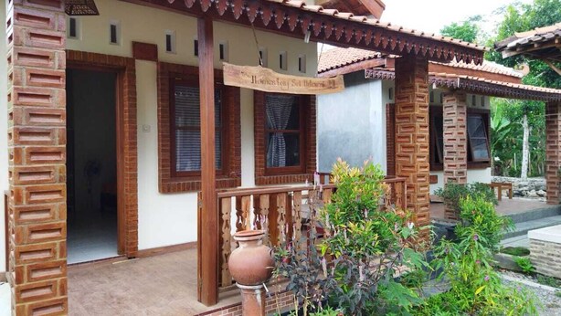 A traditional house with a tiled roof, wooden pillars, and a porch with a wooden railing.