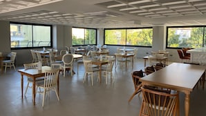 A spacious dining area with multiple tables and chairs, large windows providing natural light, and a modern ceiling design. - GRAND ÖZALP AİRPORT HOTEL (Ortaca)