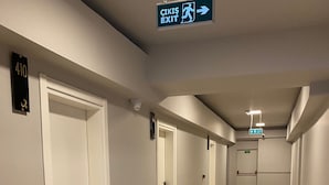 A corridor with white doors, a sign indicating an exit, and a number 410 sign on the wall. - GRAND ÖZALP AİRPORT HOTEL (Ortaca)