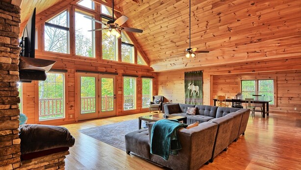 A spacious log cabin interior with a large living area, a dining table, and a fireplace. - Escape to Daltons Creek Cabin in Creston, NC, perfect for family fun! (Creston)
