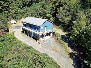 Ein blaues Haus mit Veranda, umgeben von Bäumen und einem Kiesweg.