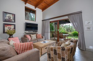 A living room with a TV, sofas, a coffee table, and a view of the garden.