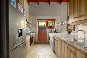 A compact kitchen with stainless steel appliances, wooden cabinets, and a built-in washer and dryer.