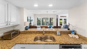 A kitchen with granite countertops, stainless steel sink, and white cabinets.