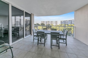 Enjoy dining or socializing on the balcony with a table and chairs, taking in the views of the surrounding residential area and palm trees.