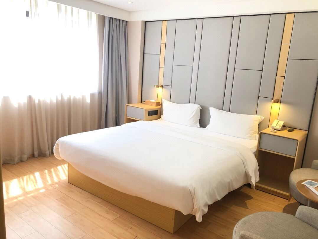 A hotel room with a large bed, bedside tables with lamps, a small round table, and a view of the outdoors.