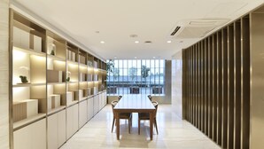 A modern interior with a long table and chairs, a built-in shelving unit, and a view through large windows. - Ji Hotel (Shanghai)
