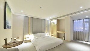 A modern hotel room with a large bed, bedside tables, a seating area, and a large window. - Ji Hotel (Shanghai)