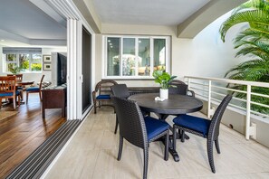 Uma área de refeições com mesa redonda e cadeiras de vime, uma janela grande e vista para o verde.